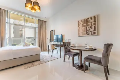 a bedroom with a bed and a table and chairs at Furnished Studio Near Circle Mall, Close to Parks, Jogging Tracks, Bus Stops And Grocery Stores - Damac Ghalia, JVC by Deluxe Holiday Homes in Dubai