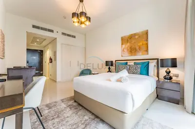 a bedroom with a large white bed and a desk at Furnished Studio Near Circle Mall, Close to Parks, Jogging Tracks, Bus Stops And Grocery Stores - Damac Ghalia, JVC by Deluxe Holiday Homes in Dubai