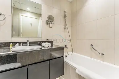 a bathroom with a sink and a tub and a mirror at Furnished Studio Near Circle Mall, Close to Parks, Jogging Tracks, Bus Stops And Grocery Stores - Damac Ghalia, JVC by Deluxe Holiday Homes in Dubai