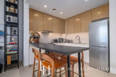 a kitchen with a counter with chairs and a refrigerator at LUX 52 42 Deluxe Marina View Suite 3 in Dubai