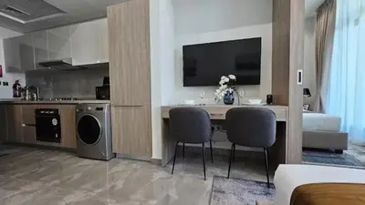 a kitchen and living room with a table and chairs at Studio Luxe Dubai South in Dubai