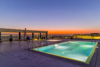a swimming pool on top of a building with a sunset at The Executive Nest -1BR in Dubai in Dubai
