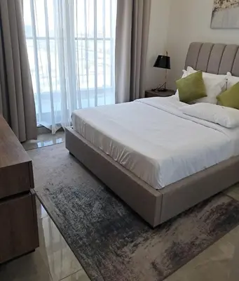 a bedroom with a large bed with white sheets and green pillows at The Executive Nest -1BR in Dubai in Dubai