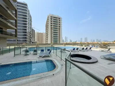 a building with a swimming pool and chairs and a building at Vogue Sports City Elite near First Avenue Mall, One Bedroom Apartment with Balcony and Vibrant Community View, Access to all Amenities in Dubai