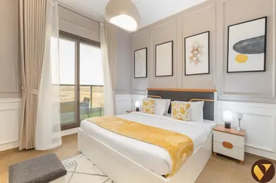 a white bedroom with a large bed and a window at Vogue Sports City Elite near First Avenue Mall, One Bedroom Apartment with Balcony and Vibrant Community View, Access to all Amenities in Dubai