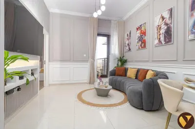 a living room with a gray couch and a table at Vogue Sports City Elite near First Avenue Mall, One Bedroom Apartment with Balcony and Vibrant Community View, Access to all Amenities in Dubai