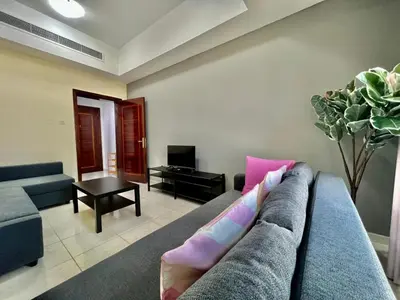 a living room with a blue couch and pink pillows at Close to The World Trade Center and DIFC in Dubai