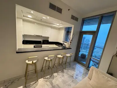 a kitchen with bar stools and a large window at Luxury 2BR Canal front & Burj Khalifa views- High Floor in Dubai