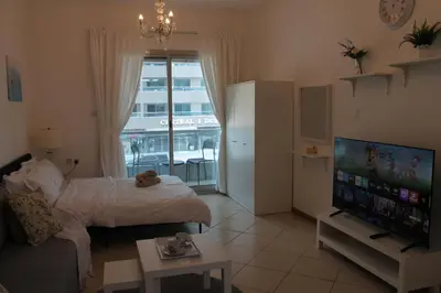 a living room with a bed and a flat screen tv at Studio apartment walking distance to metro and beach in Marina in Dubai