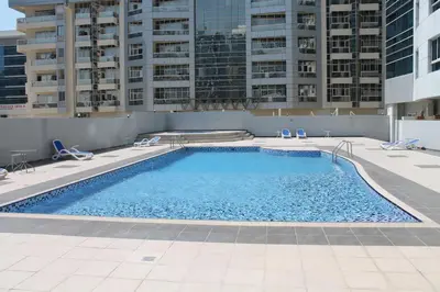 a swimming pool with chairs and buildings in the background at Studio apartment walking distance to metro and beach in Marina in Dubai