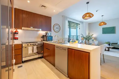 a kitchen with wooden cabinets and a counter top at Urban Beachside 2BR with a Glimpse of Burj Khalifa, Near Jumeirah Beaches, Short Drive to Mercato Mall, La Sirene Building 4, Jumeirah by Deluxe Holiday Homes in Dubai