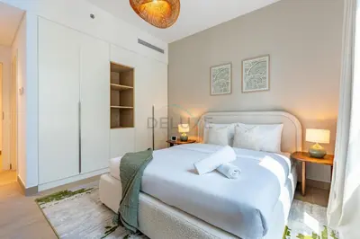 a bedroom with a large white bed with two tables at Urban Beachside 2BR with a Glimpse of Burj Khalifa, Near Jumeirah Beaches, Short Drive to Mercato Mall, La Sirene Building 4, Jumeirah by Deluxe Holiday Homes in Dubai