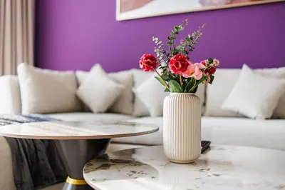 a vase with flowers on a table in a living room at SettlerHomes - Elite 2BR With Private Jacuzzi Oasis in Dubai