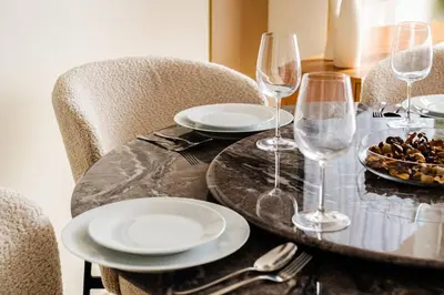 a table with plates and wine glasses on it at SettlerHomes - Elite 2BR With Private Jacuzzi Oasis in Dubai