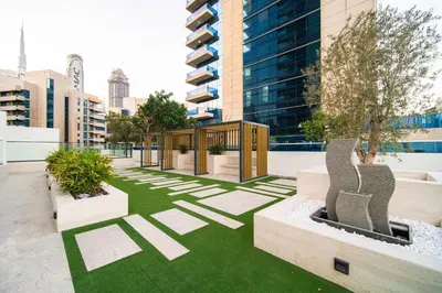a courtyard with grass and benches in a city at SettlerHomes - Elite 2BR With Private Jacuzzi Oasis in Dubai