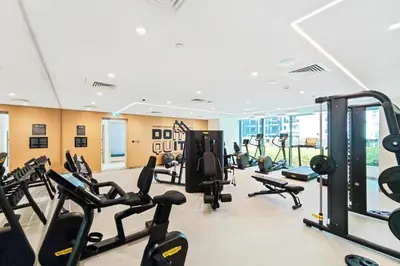 a gym with a lot of treadmills and machines at FAM Living - Elegant 2BR with Park & Creek Panorama in Dubai