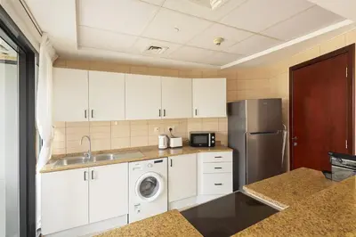 a kitchen with white cabinets and a stainless steel refrigerator at Modern Studio with Marina Skyline view in JLT - Prime Location near Metro in Dubai