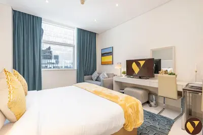 a hotel room with a bed and a desk with a computer at Vogue Business Bay Damac Cour Jardin close to Downtown, Burj Khalifa and Dubai Mall, Studio Apartment with City View, Access to all Amenities in Dubai