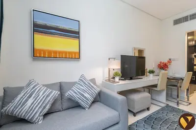 a living room with a couch and a desk with a television at Vogue Business Bay Damac Cour Jardin close to Downtown, Burj Khalifa and Dubai Mall, Studio Apartment with City View, Access to all Amenities in Dubai