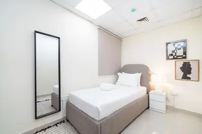 a bedroom with a white bed and a large mirror at Bright and Stylish 2 Bed Home Opposite Circle Mall in Dubai