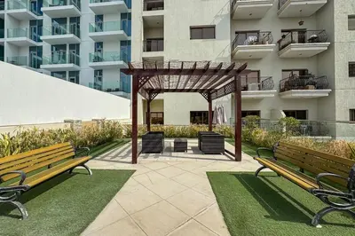 two park benches in front of a building at Bright and Stylish 2 Bed Home Opposite Circle Mall in Dubai