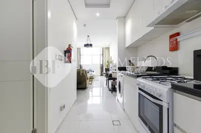 a kitchen with white appliances and a long hallway at Bloomfields Elegant Stu Damac Ghalia in Dubai
