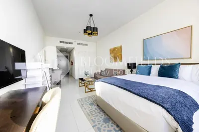 a bedroom with a large bed and a living room at Bloomfields Elegant Stu Damac Ghalia in Dubai