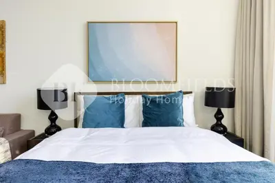 a bedroom with a bed with blue pillows and a picture at Bloomfields Elegant Stu Damac Ghalia in Dubai