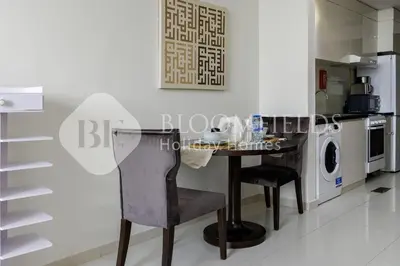 a kitchen with a table and chairs in a room at Bloomfields Elegant Stu Damac Ghalia in Dubai