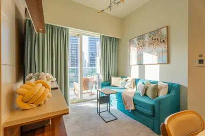 a living room with a blue couch and a window at Modern 1BR in Business Bay Balcony Pool Access in Dubai