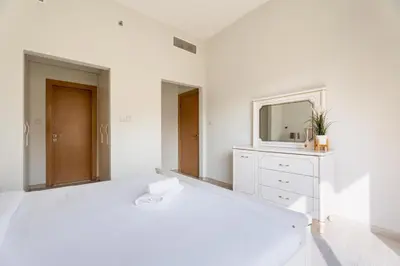 a white bathroom with a sink and a mirror at GuestReady – Relax Stay w Balcony & Pool View in Dubai
