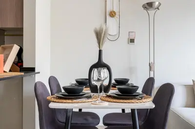 a dining room table with a black vase on it at GuestReady – Relax Stay w Balcony & Pool View in Dubai