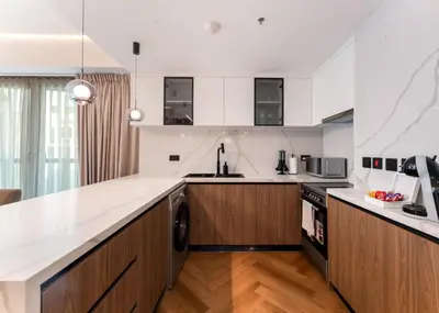 a kitchen with white countertops and wooden cabinets at Modern 2-BR in 8-BLVD WALK Downtown Dubai in Dubai
