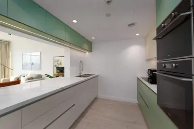 a kitchen with white countertops and green cabinets at Burj Views East, Downtown - Mint Stay in Dubai