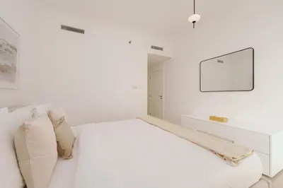 a white bedroom with a bed and a tv at Burj Views East, Downtown - Mint Stay in Dubai