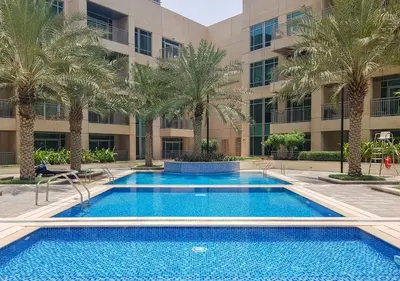 a pool with palm trees in front of a building at Burj Views East, Downtown - Mint Stay in Dubai