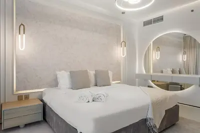 a bedroom with a large white bed and a mirror at FIRST CLASS1BR Sea View and Near Beach and Tram in Dubai