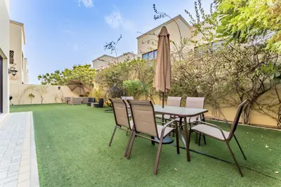 a patio with a table and chairs and an umbrella at Spacious 4BR Plus Maids Villa, Near Avenue Mall, Cycle Park & Sports Complex - 15 Mins to Downtown Dubai, Nad Al Shiba Third by Deluxe Holiday Homes in Dubai