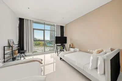 a white room with two beds and a television at FIRST CLASS Studio Infinity Pool and Luxe Vibes in Dubai