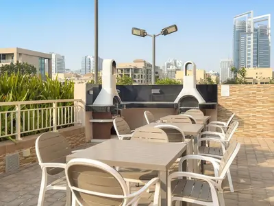 a row of tables and chairs on a rooftop patio at FIRST CLASS 1BR Modern Urban Retreat in Dubai