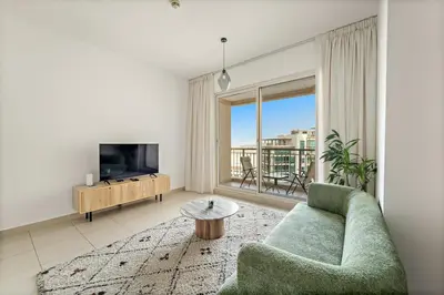 a living room with a couch and a television at FIRST CLASS 1BR Modern Urban Retreat in Dubai