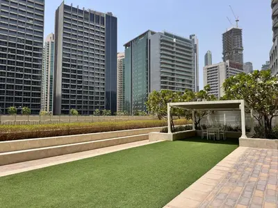 a garden with a gazebo and green grass at Cozy 1BR at Reva Residences in Dubai