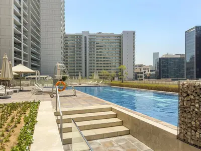 a swimming pool in a city with tall buildings at Cozy 1BR at Reva Residences in Dubai