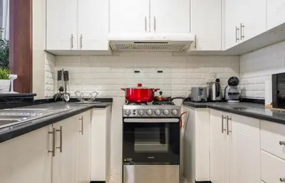 a kitchen with white cabinets and a red pot on the stove at Luxury 1BR with Pool, Gym Canal & Burj Khalifa view in Dubai
