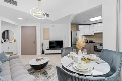 a kitchen and living room with a table and chairs at Stylish Apartment with Pool, Gym and Skyline View Dubai Gate in Dubai