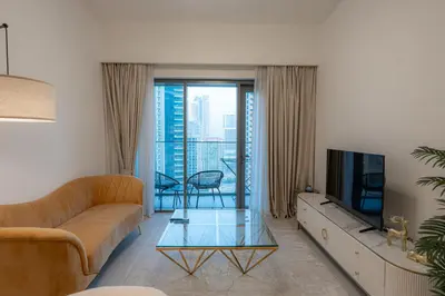 a living room with a couch and a tv at Modern 1BR - Fitness & Swimming Pool Access in Dubai