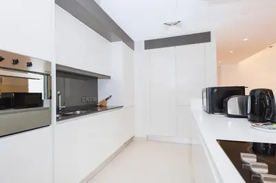 a white kitchen with a microwave and a counter at Spacious Luxury 1BR Modern Design Bluewaters in Dubai