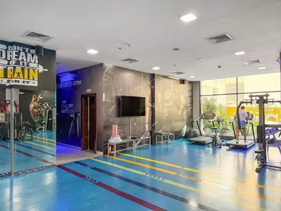 a gym with a blue floor and a tv at Silkhaus Classic 1BDR Stay in Jumeirah Village in Dubai
