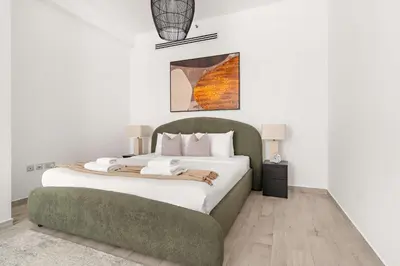 a bedroom with a large bed and a green couch at Silkhaus Classic 1BDR Stay in Jumeirah Village in Dubai