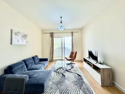 a living room with a blue couch and a television at Homes2Retreat - JVC Charm - 1BR Apt with Private Balcony in Dubai